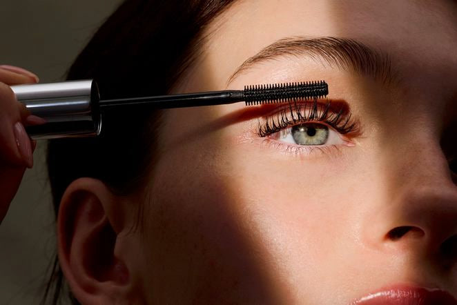 Femme appliquant du mascara sur ses cils supérieurs, gros plan de l'œil