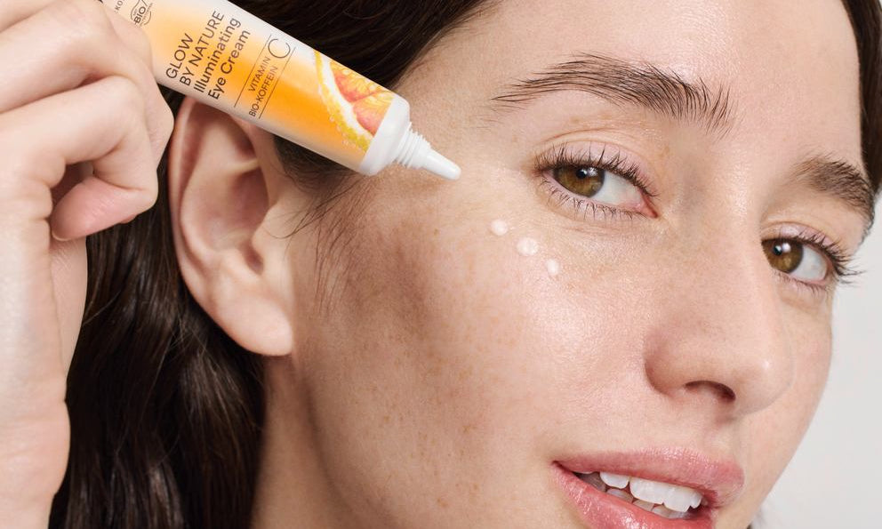 Femme applique crème pour les yeux glow by nature sous l'œil, gros plan