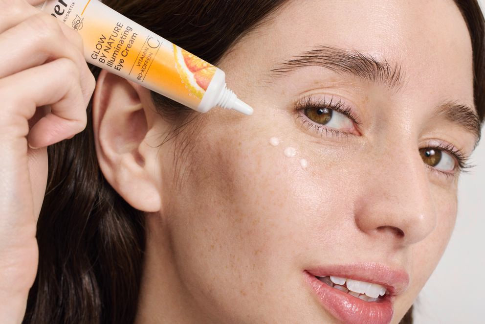 Femme applique crème pour les yeux glow by nature sous l'œil, gros plan
