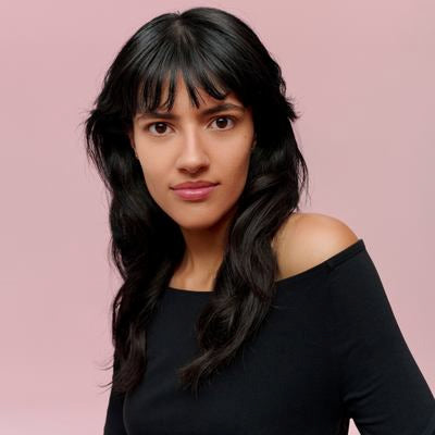 Portrait d'une femme aux cheveux noirs avec frange sur fond rose