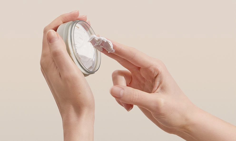 Doigt prend crème d'un pot, gros plan de la texture