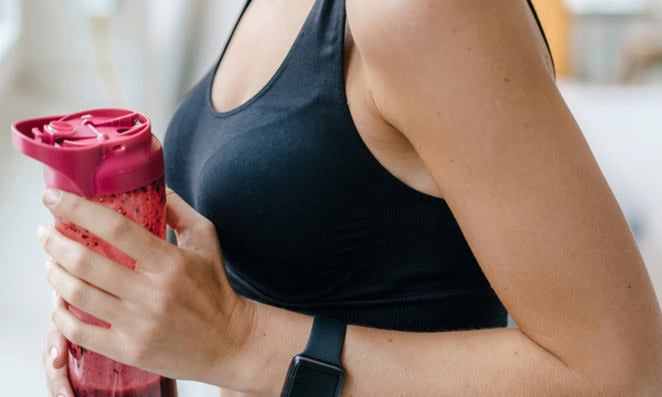 Vue d'un torse féminin en haut de sport tenant une bouteille d'eau