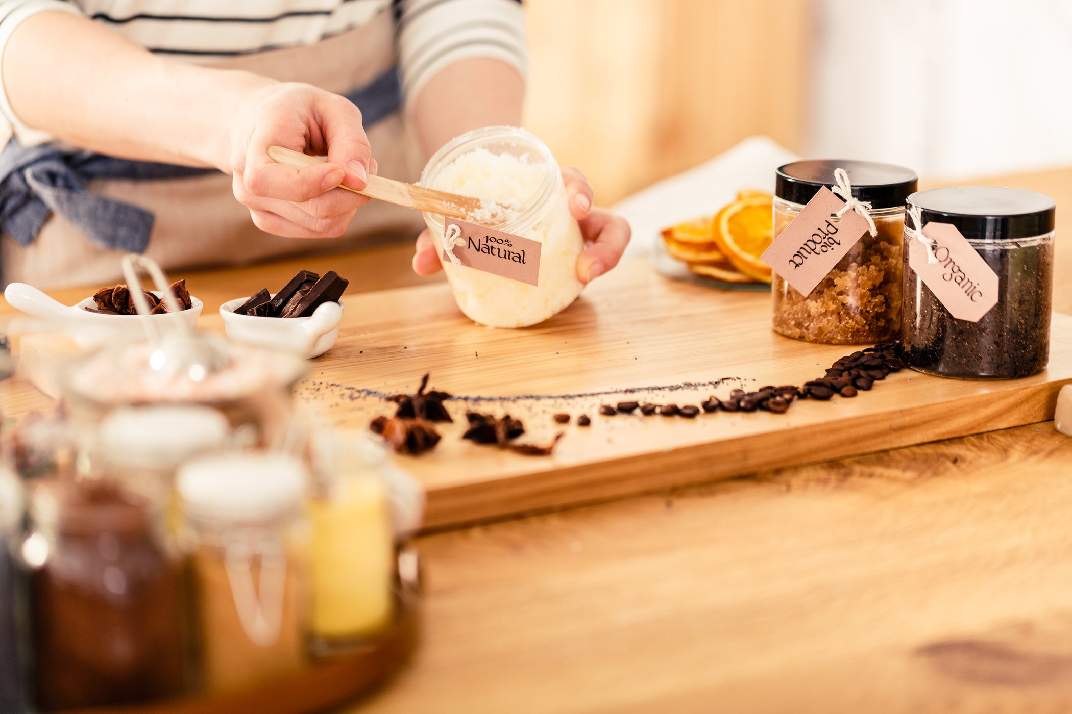 Gommage corporel DIY : personne remplissant un pot de gommage au sucre, épices et café sur une planche