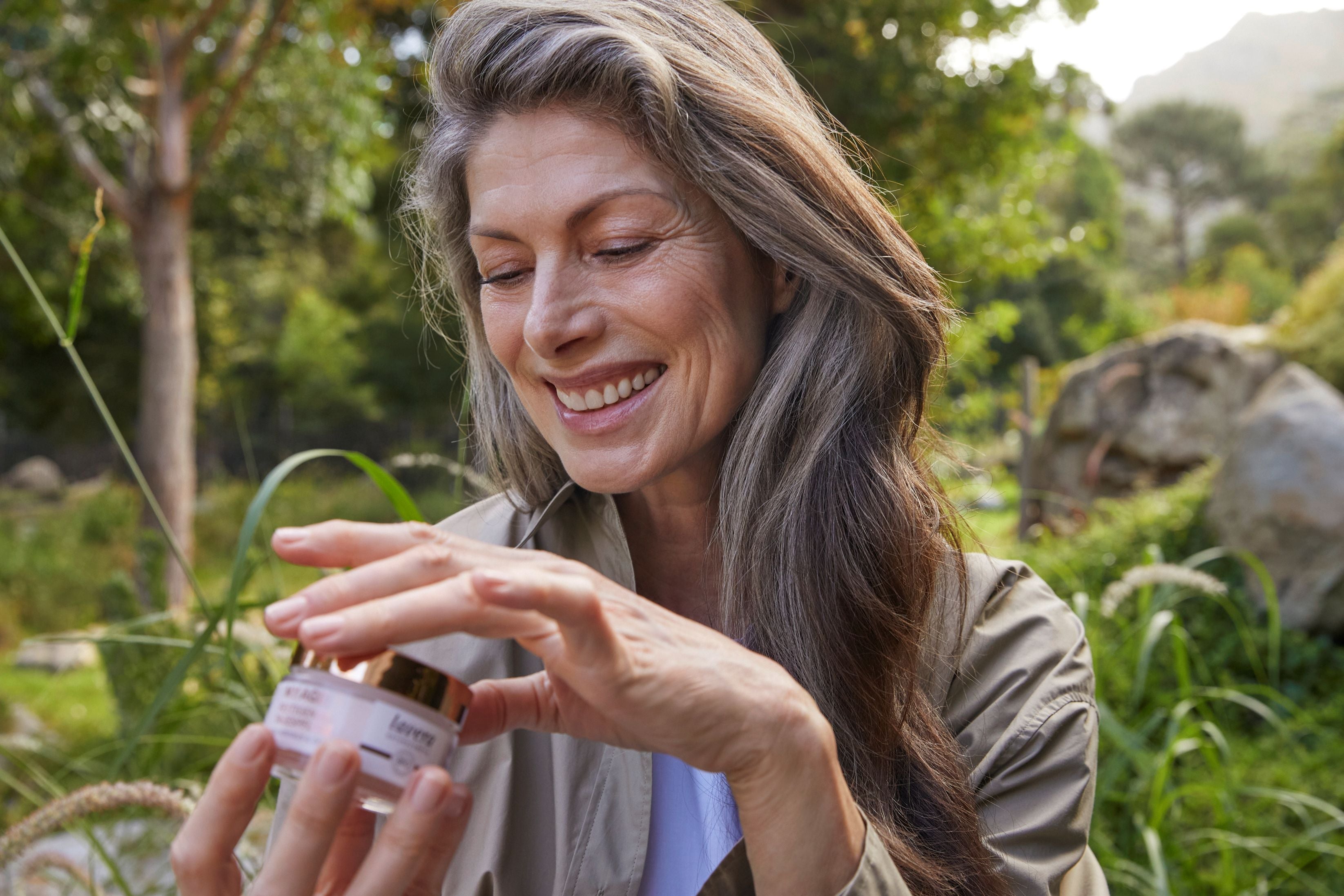 Femme dans la nature tenant crème lavera MY AGE dans les mains
