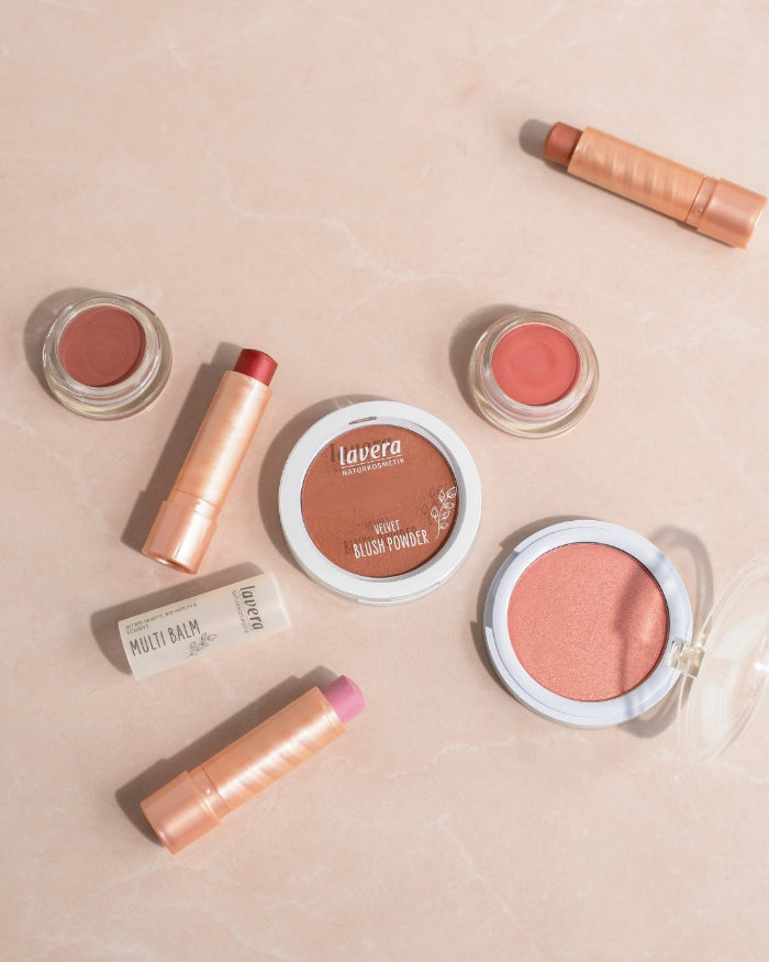 Verschiedene lavera Multibalms und Blush-Produkte in roséfarbenen Nuancen auf hellem Untergrund.