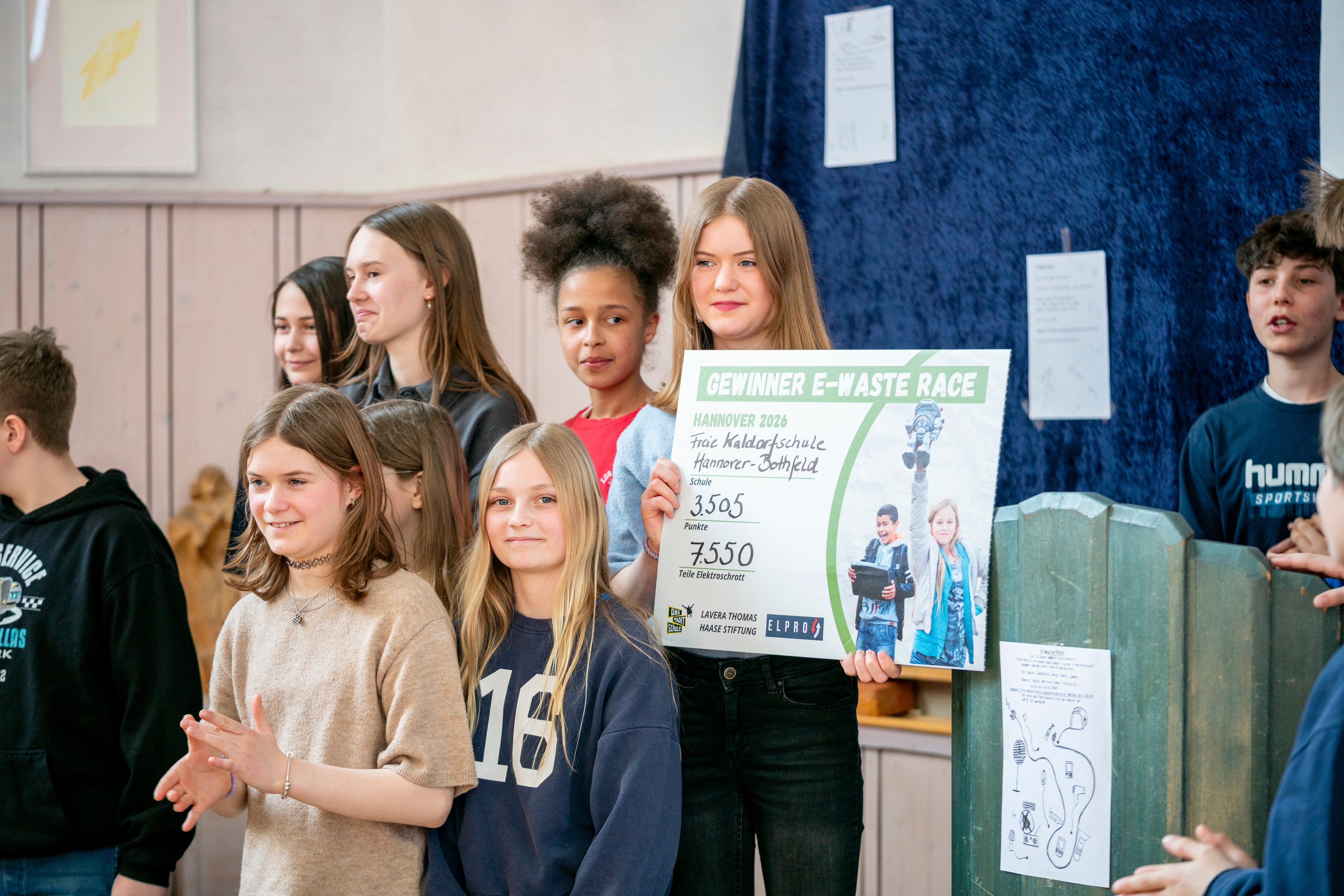 Lachende junge Mädchen, die E-Waste-Race Urkunde hochhalten