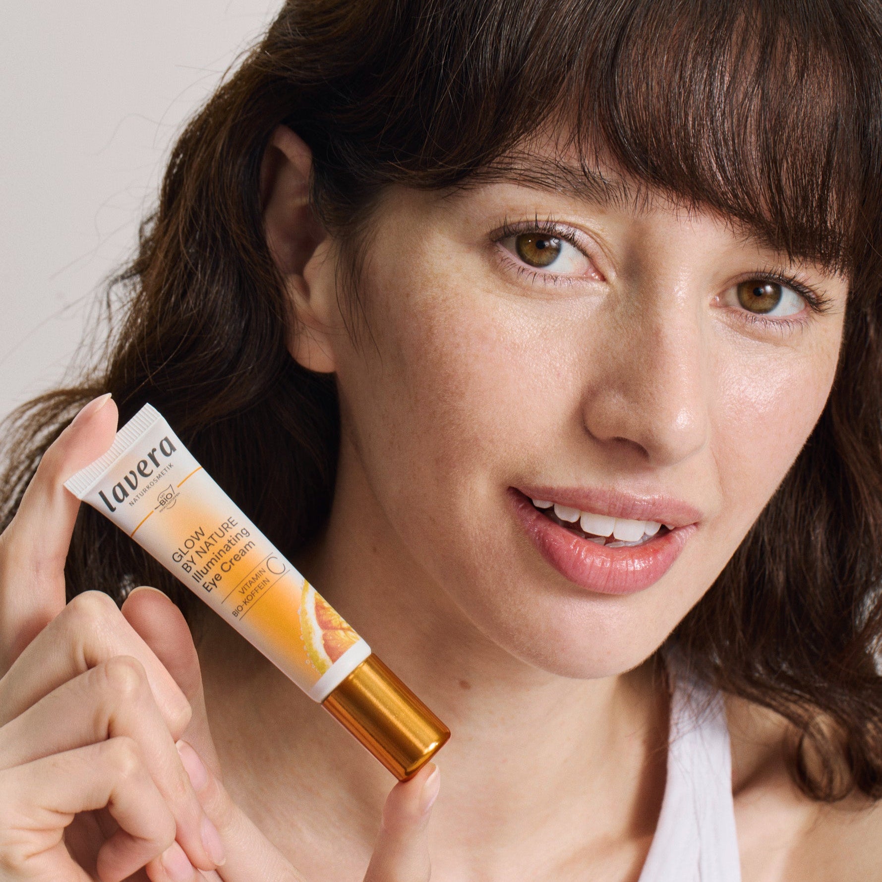 Une femme tient la lavera Glow by Nature Illuminating Eye Cream dans sa main