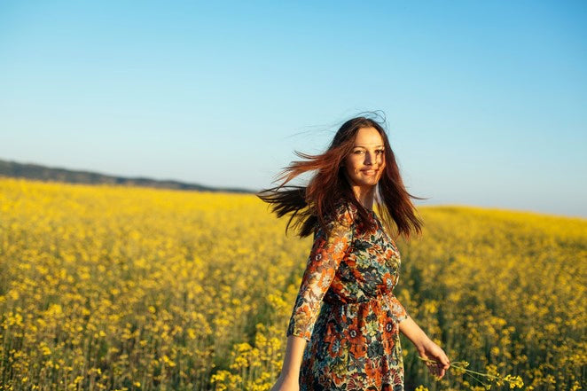 Personne marchant dans un champ de colza en fleurs au soleil.