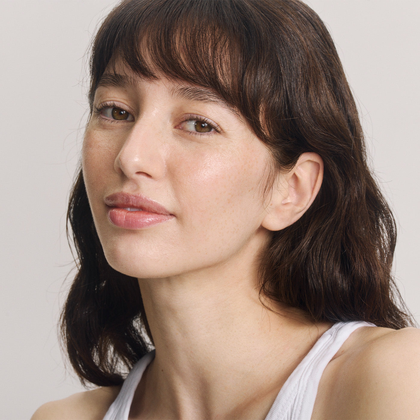 Porträt von junger Frau mit braunen Haaren, Pony und braunen Augen