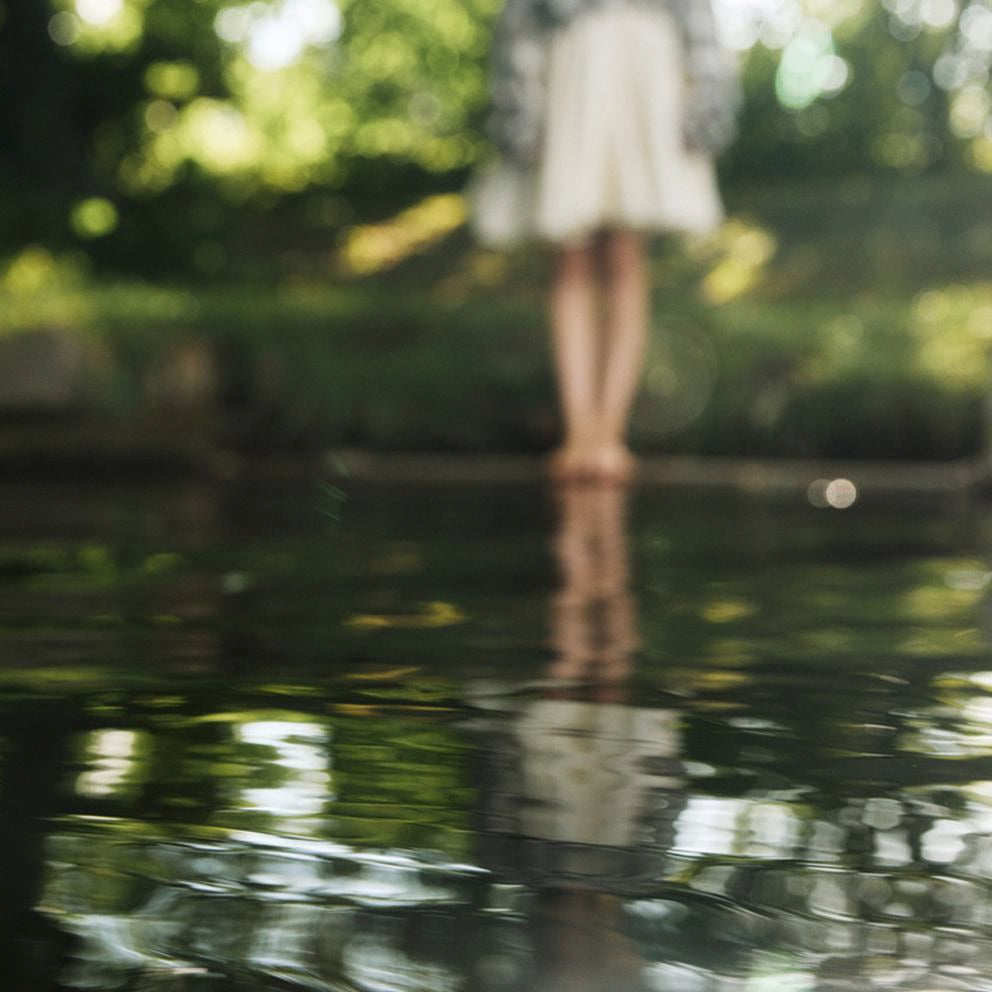 Jambes d'une femme en jupe se reflétant dans l'eau