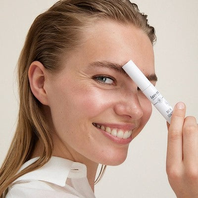 Femme souriante tenant un crayon de maquillage lavera au sourcil, gros plan