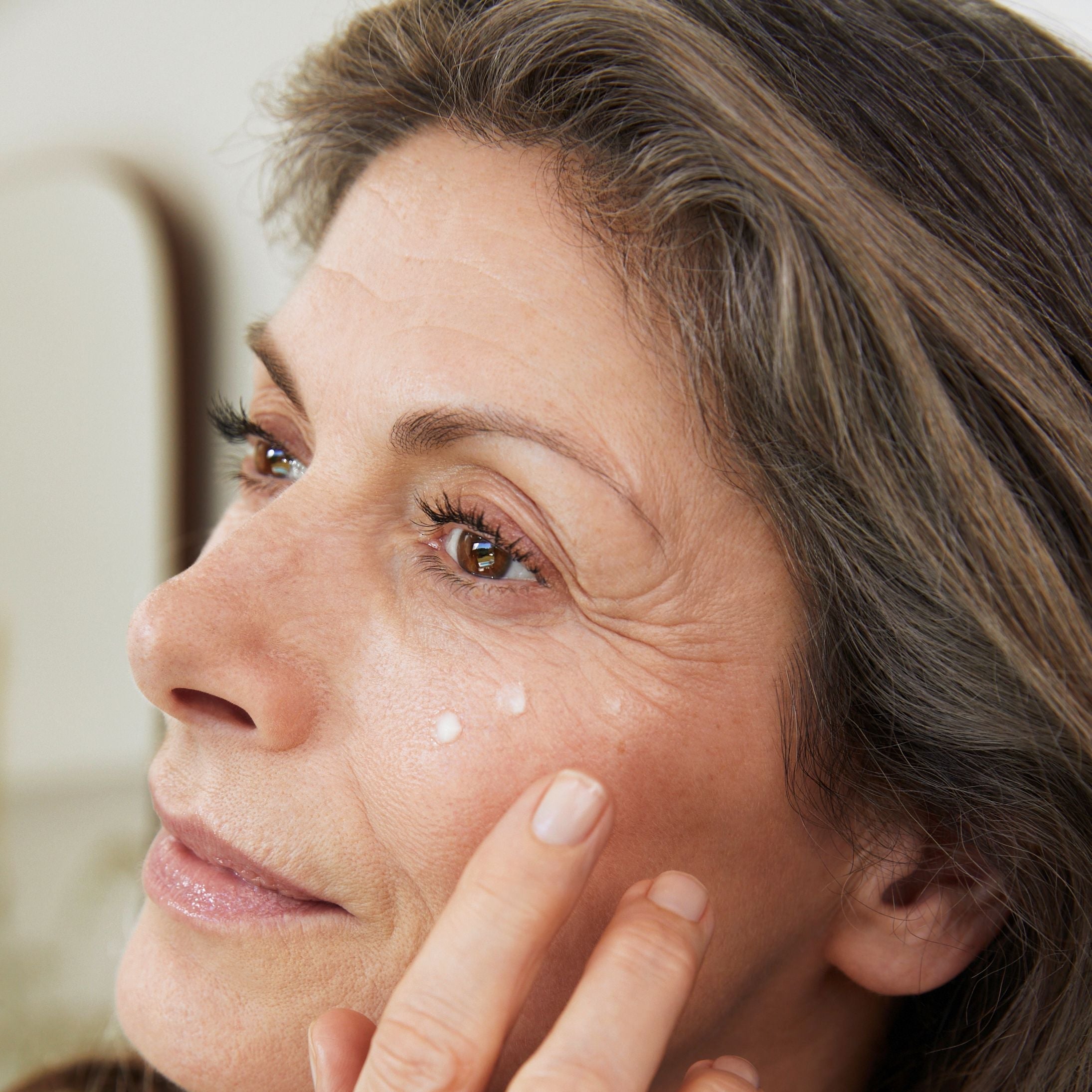 Femme applique crème sous l'œil