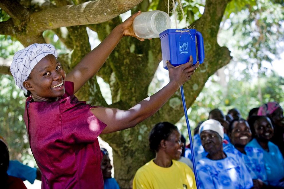 Femme à la peau foncée avec turban verse de l'eau dans un entonnoir fait maison