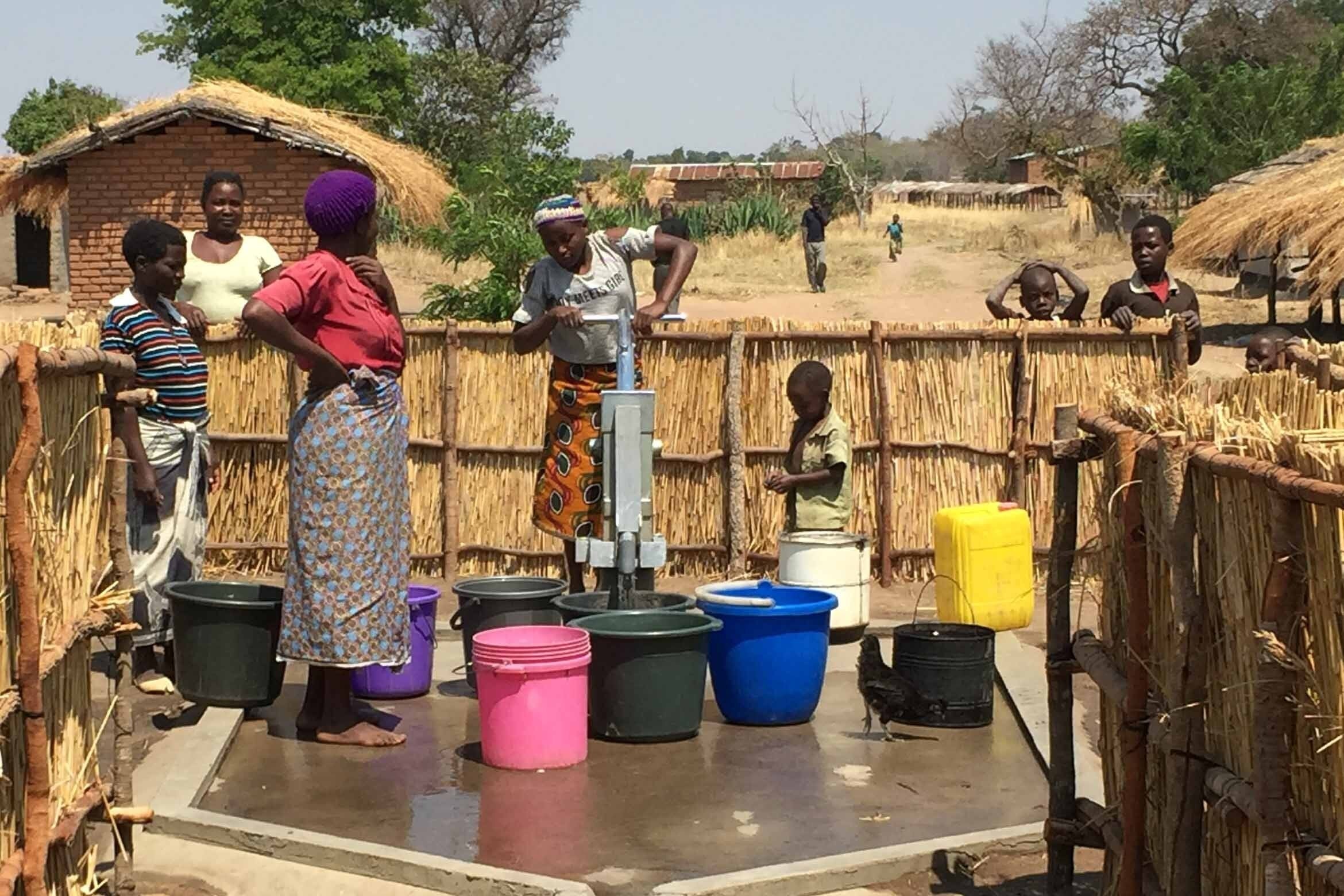 Groupe de femmes et d'enfants africains pompant de l'eau d'un puits