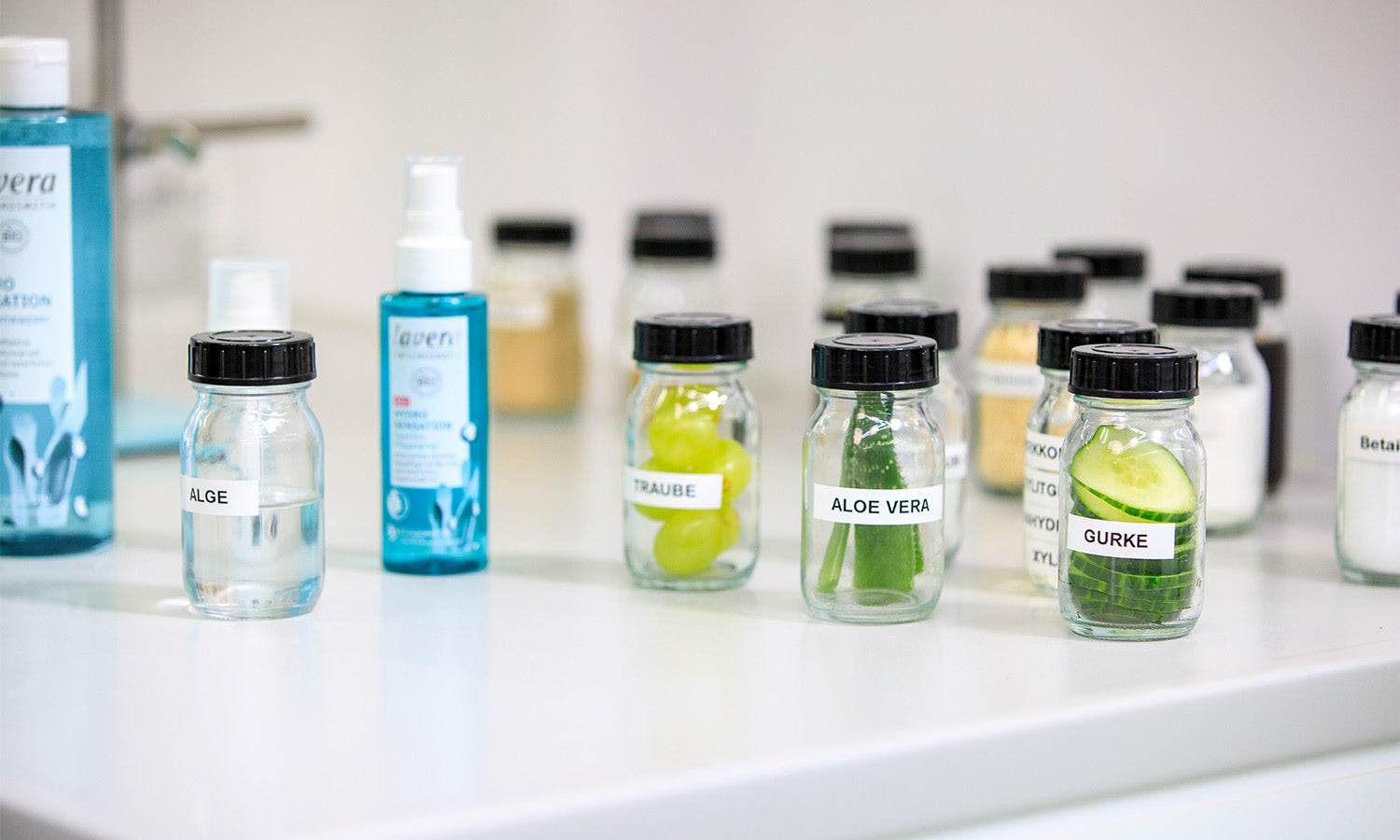 Différents ingrédients comme concombre et aloe vera dans de petits verres en laboratoire