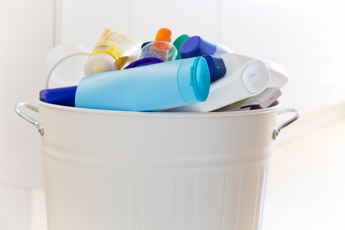 Unterschiedliche Kosmetik-Verpackungen in einem weißen Mülleimer
