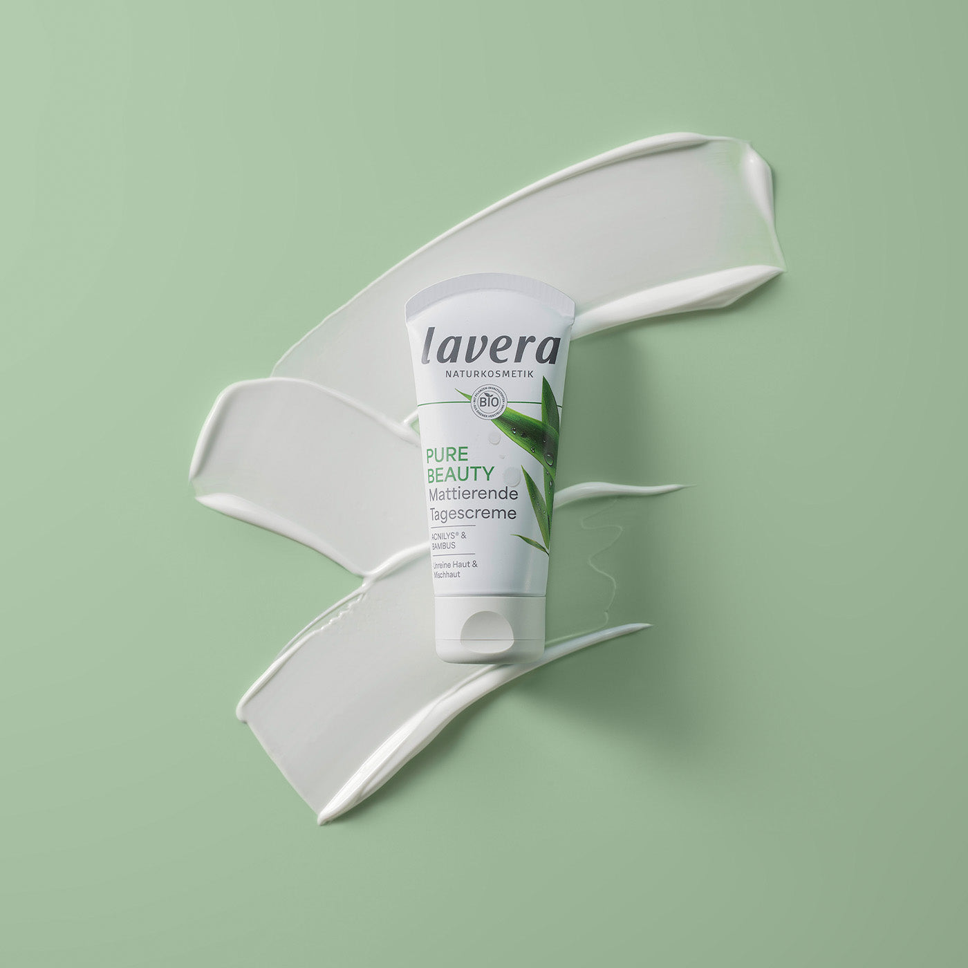 Nahaufnahme Pure Beauty mattierende Tagescreme vor weißem creme Swoosh auf grünem Hintergrund