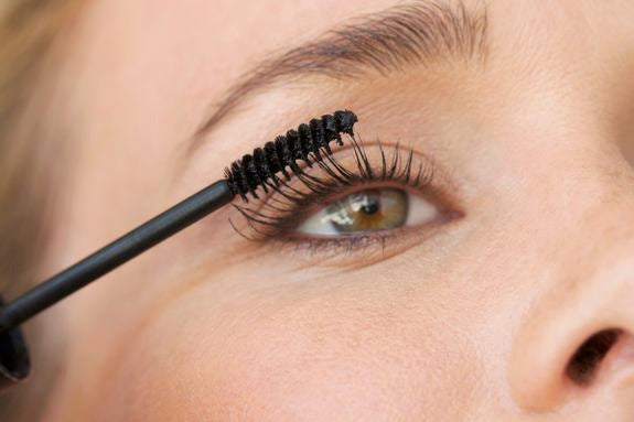 Gros plan d'un œil lors de l'application de mascara avec une brosse