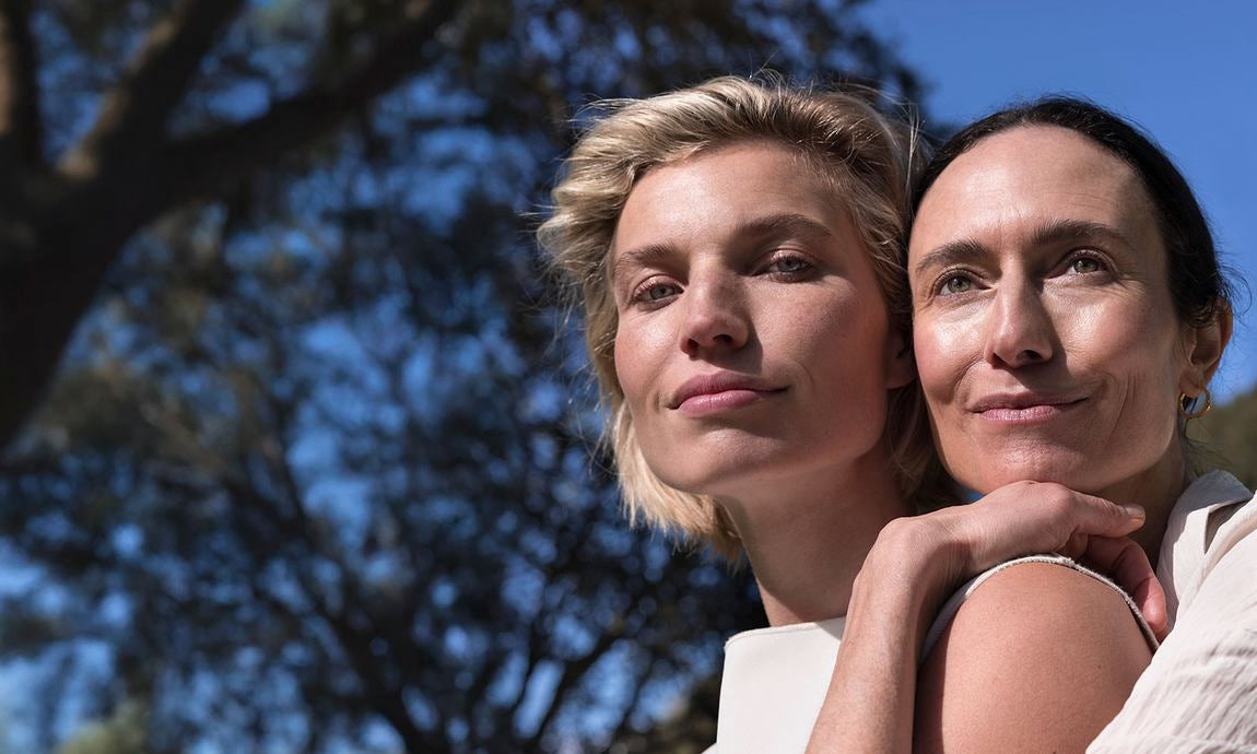 Deux femmes au soleil, l'une enlace l'autre, portrait en extérieur