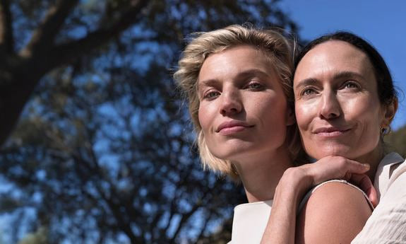 Deux femmes à l'extérieur avec look naturel, étroitement appuyées l'une contre l'autre