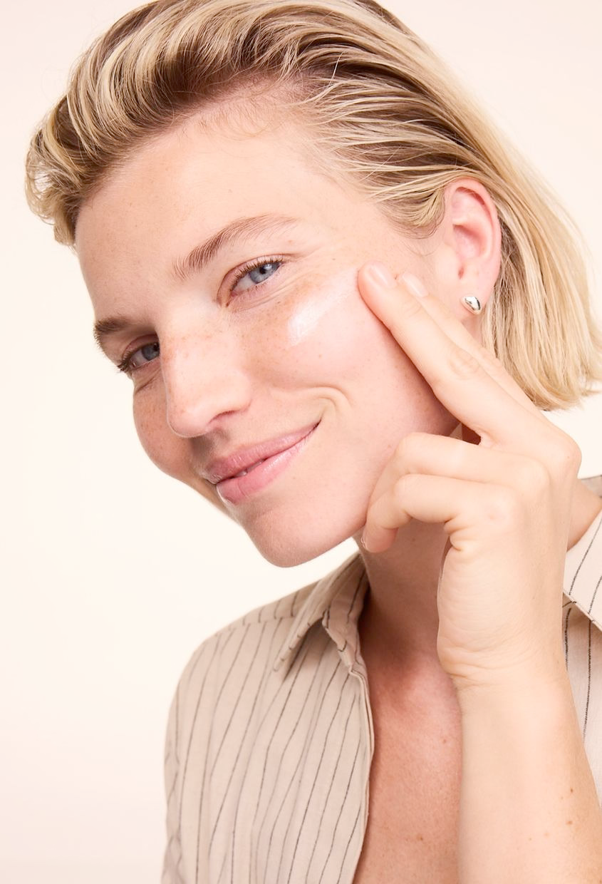 Frau schaut in die Kamera und cremt sich ein