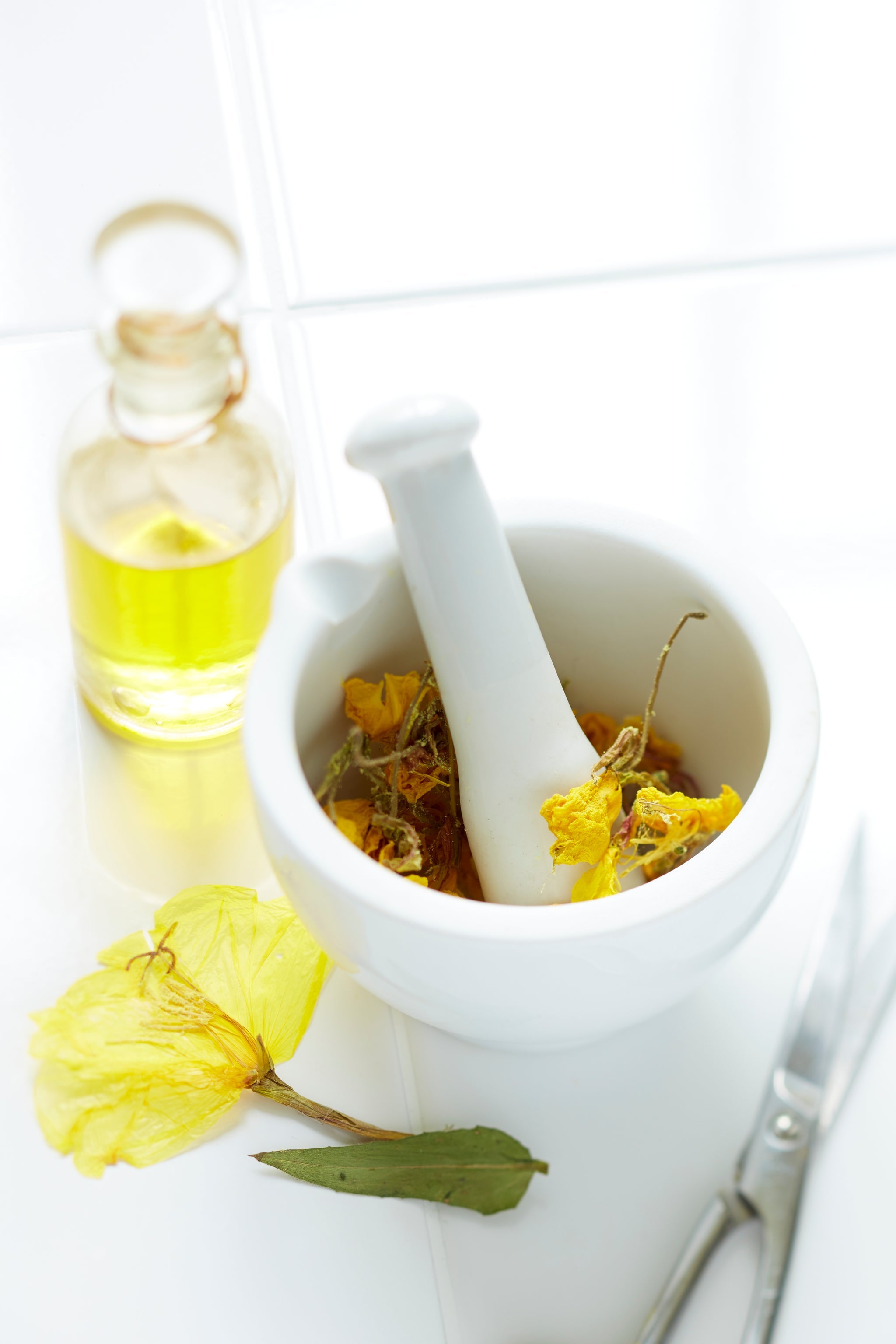 Mörser mit getrockneten Nachtkerzenblüten und Fläschchen Nachtkerzenöl.