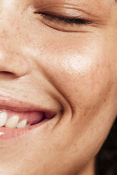 Nahaufnahme eines lächelnden Gesichts mit natürlicher Hautstruktur