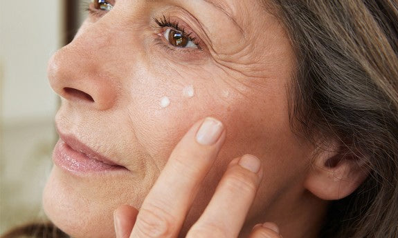 Femme mature appliquant une noisette de crème sous son œil
