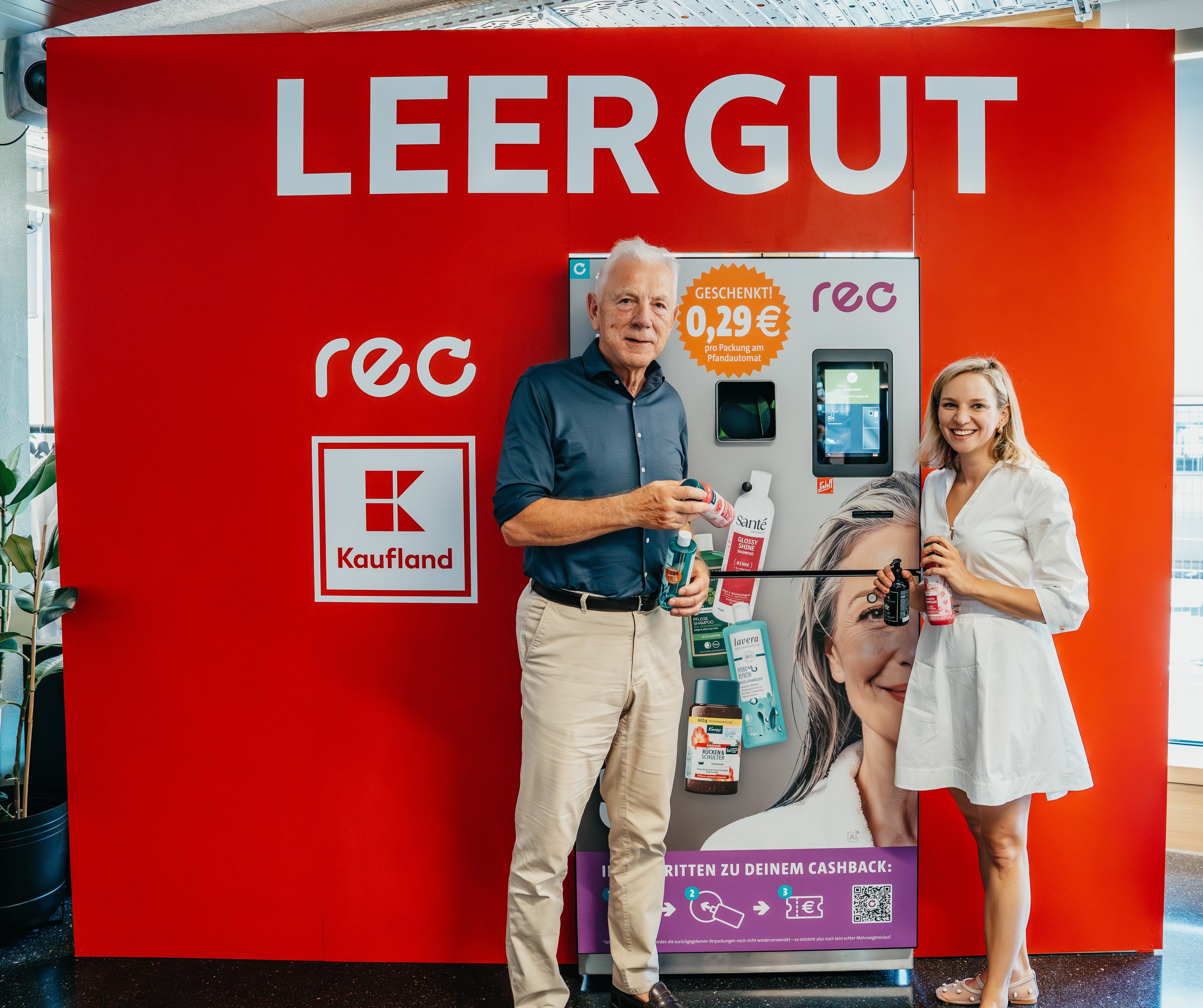 Älerer Mann und junge Frau vor einem roten Leergutautomaten