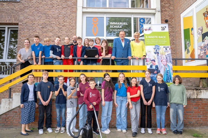 Schulklasse steht vor einer Schule 