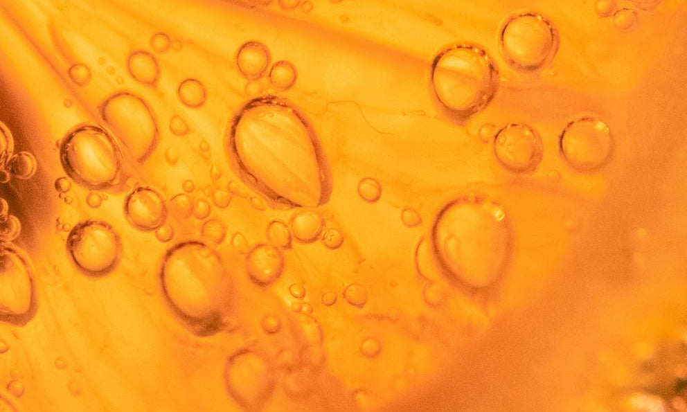 Macro : texture d'huile orangée avec bulles d'air, fond de sérum