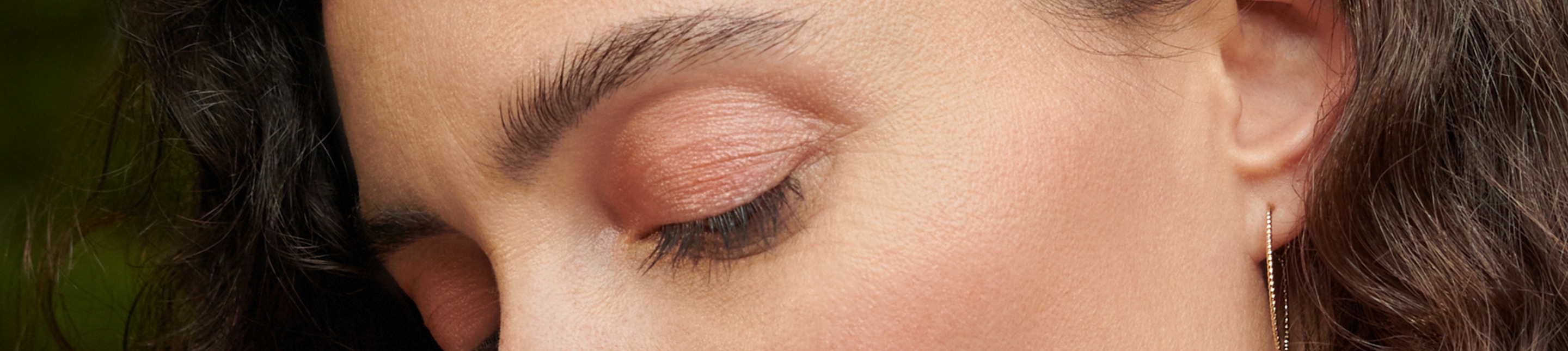 La moitié supérieure du visage d’une femme brune au maquillage discret, les yeux fermés dans une expression détendue