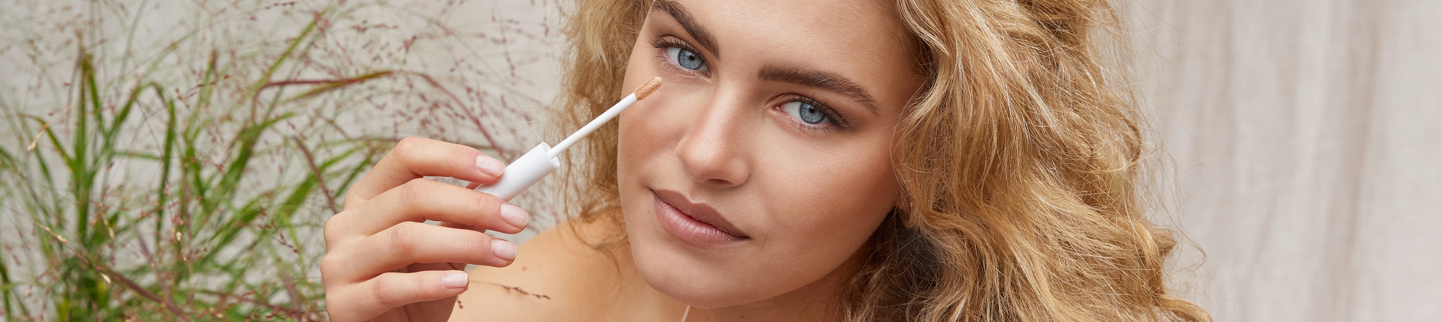Make up lavera Naturkosmetik Une femme blonde au maquillage subtil regarde directement la caméra et présente le Radiant Skin Concealer de lavera cosmétiques naturels