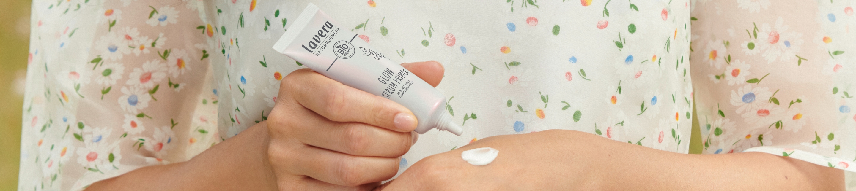 De douces mains féminines appliquent le sérum primer lavera cosmétiques naturels sur le dos de la main, mettant en valeur la texture