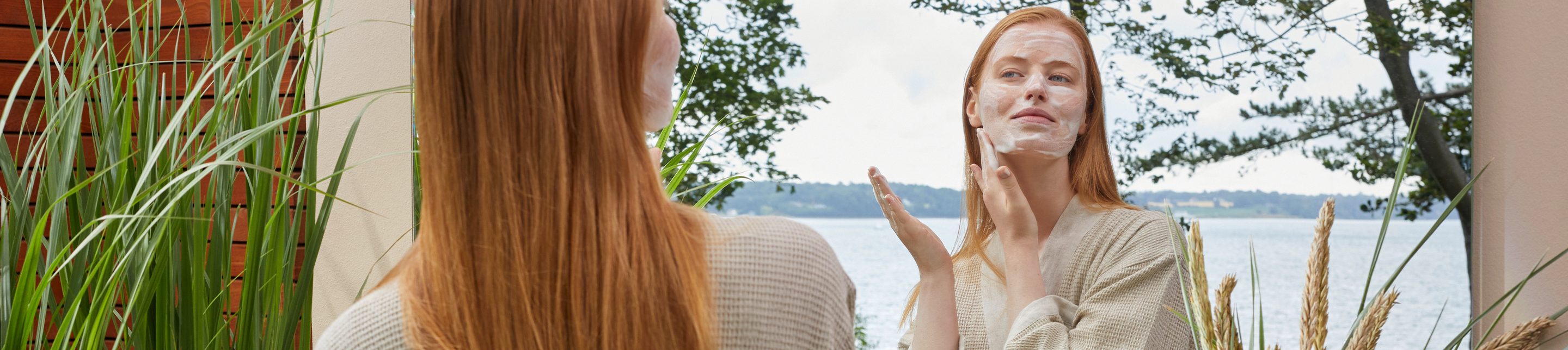 Gesichtsreinigung Pflege lavera Naturkosmetik Femme rousse regardant dans le miroir et nettoyant son visage avec le lait nettoyant lavera cosmétiques naturels